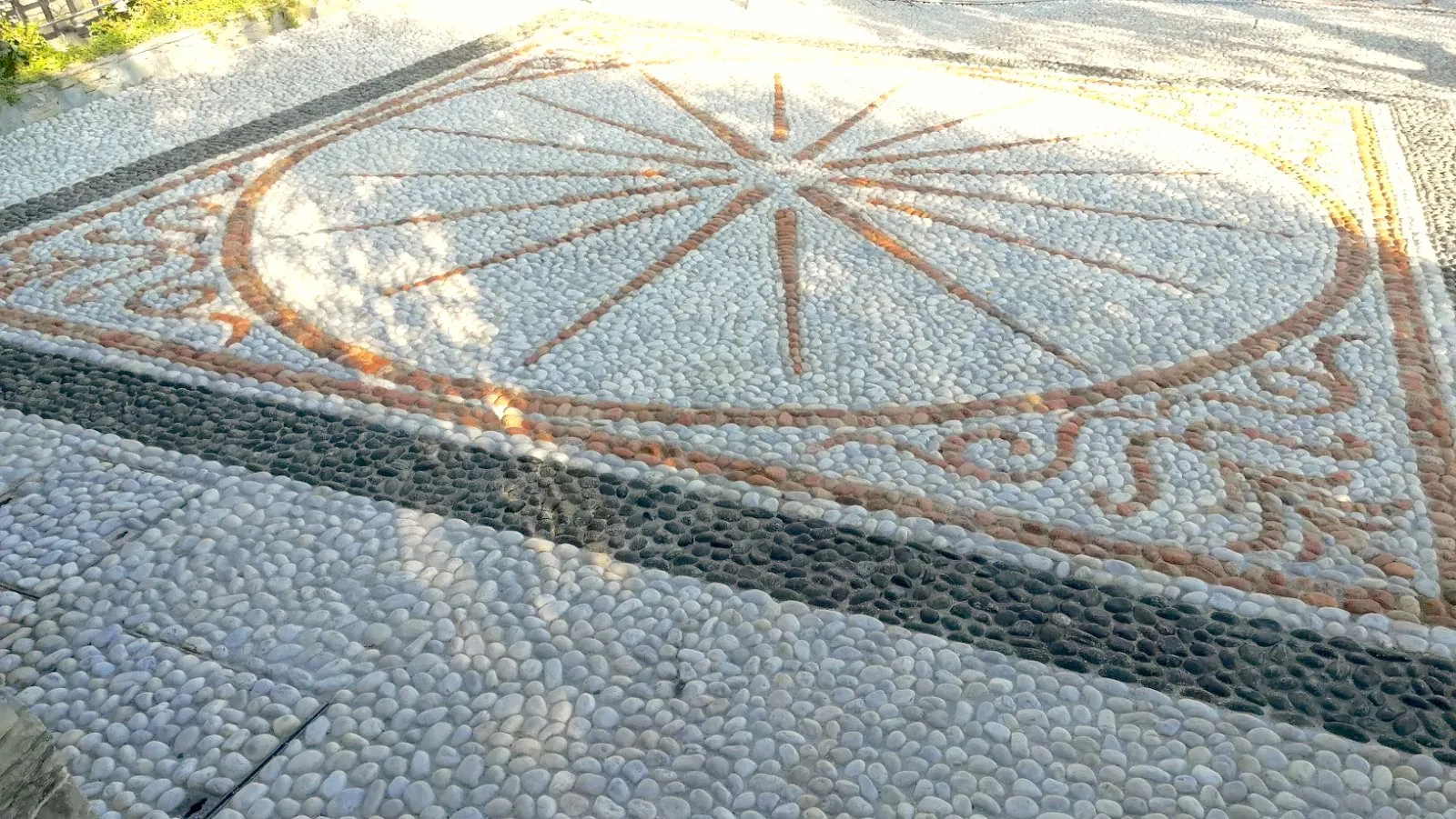Pavimento in ciottoli di fiume bianchi e scuri con decorazione a rosa dei venti
