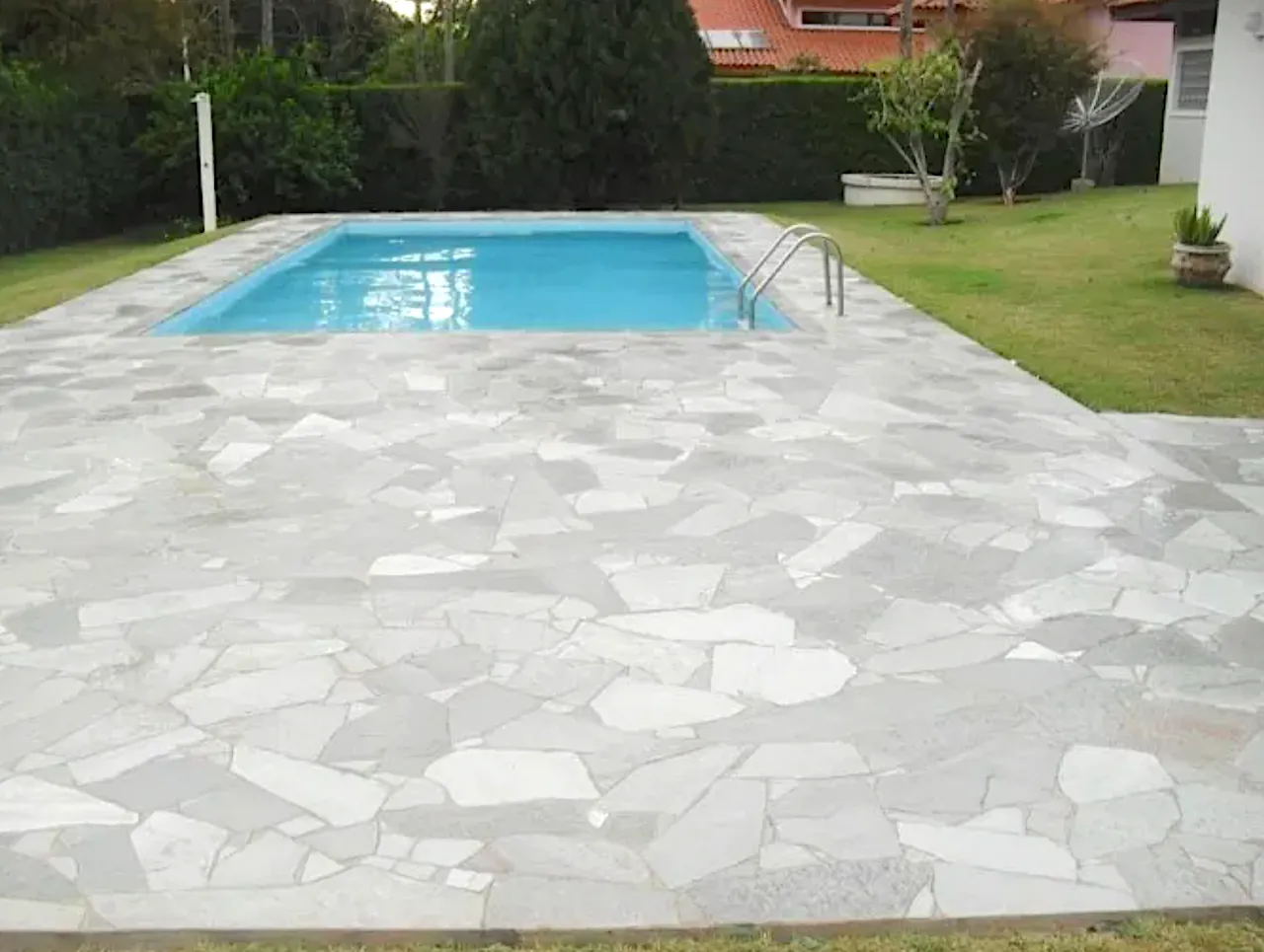 Pavimentazione a mosaico in quarzite brasiliana bianca intorno a una piscina in giardino